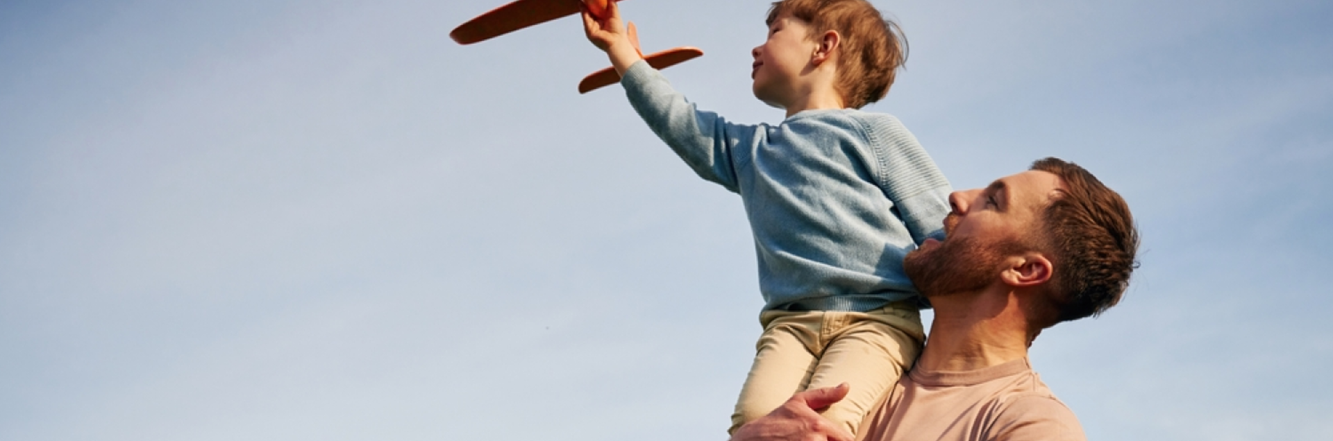 Father holding his son flying a toy plane