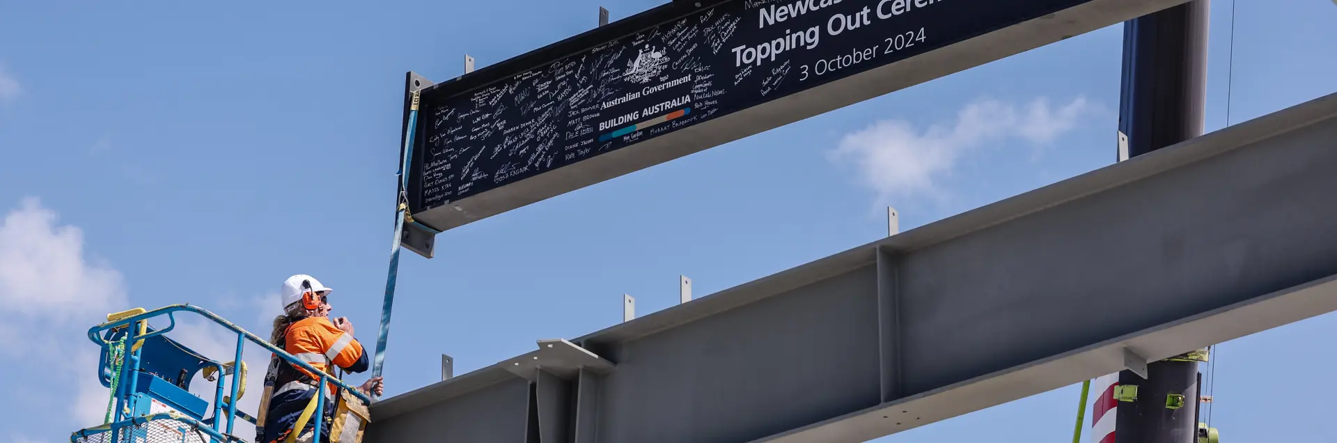 Image of final steel beam being lifted into place at Newcastle Airport