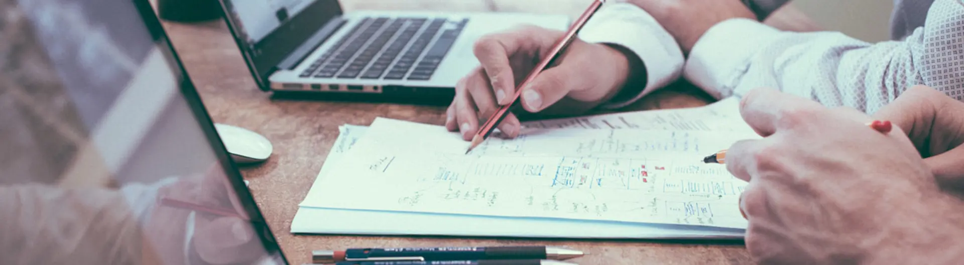 People working on laptops and writing on paper